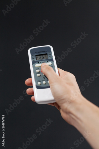 Wallpaper Mural Hand using a remote control to activating air conditioning  on the dark background Torontodigital.ca