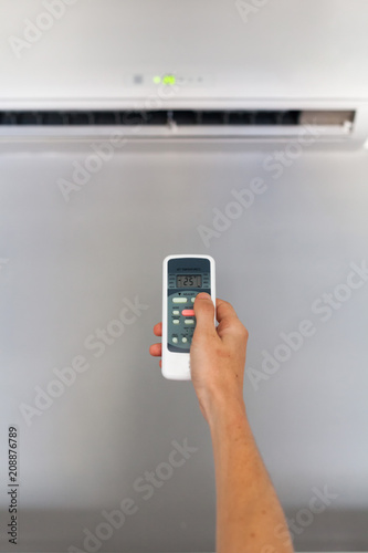 Hand using a remote control to activating air conditioning