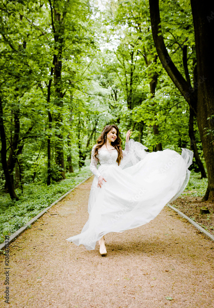 An gorgeous girl in a white dress walks along the path in the park An gorgeous girl in a white dress walks along the path in the park