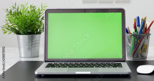 4K : A laptop computer with a key green screen set on work office table. Dolly in