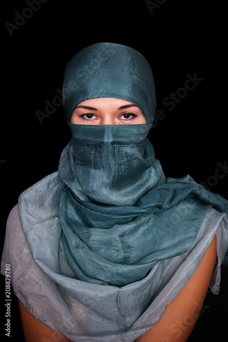 Portrait of a young woman wearing hijab on black background.