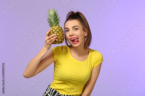 Emotional young woman with pineapple on color background