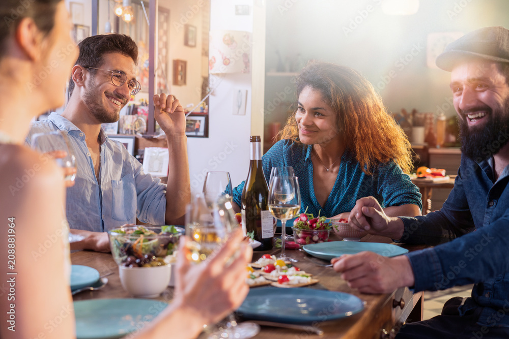 Mixed group of friends having fun while sharing a meal 