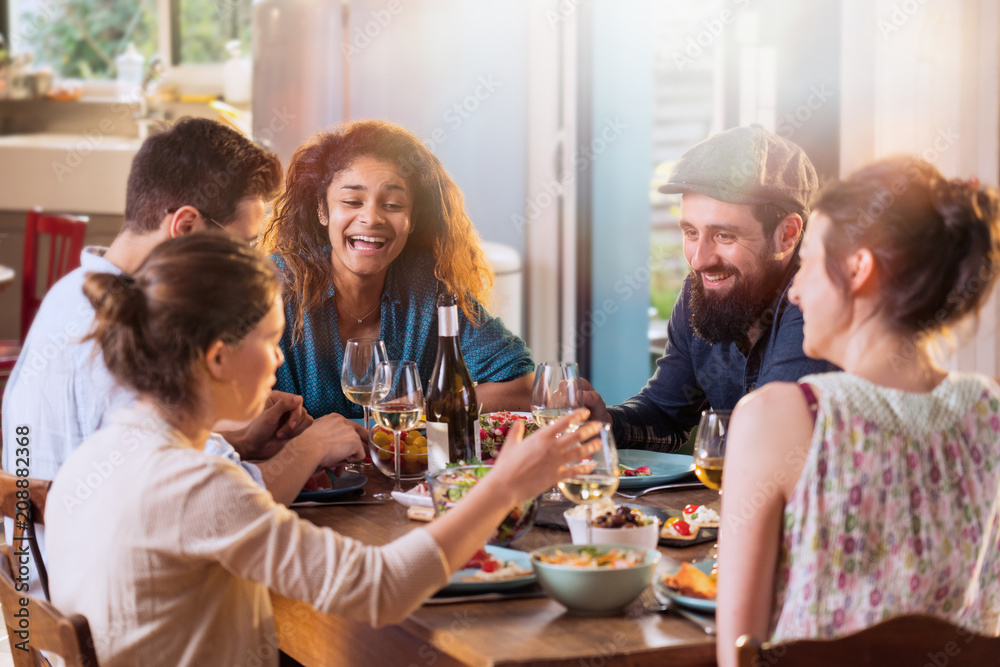 Mixed group of friends having fun while sharing a meal 