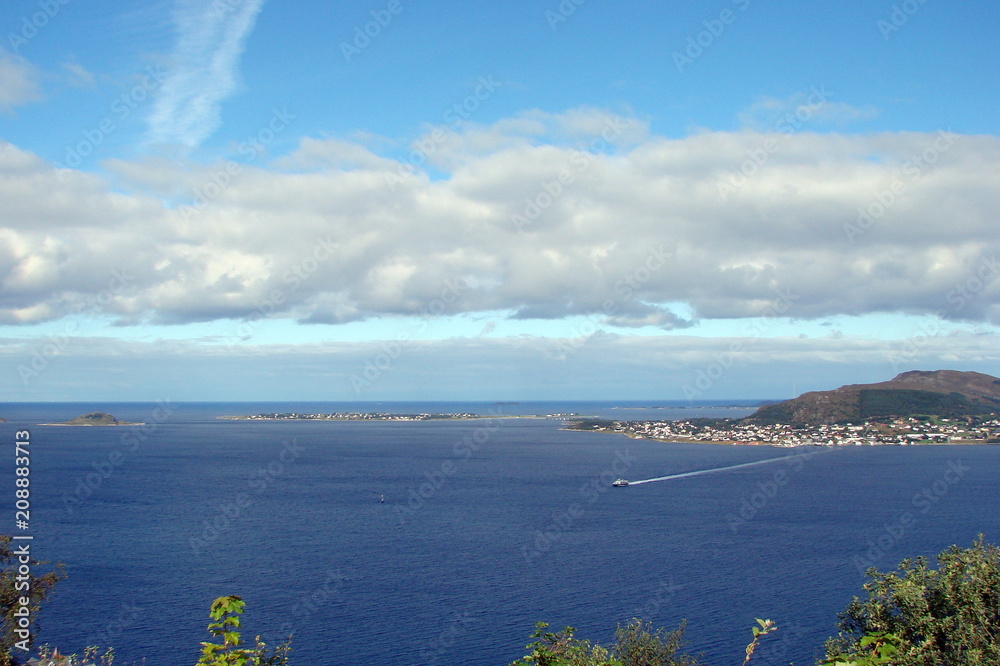 A view from a bird's eye view of a cloudy lane of blue sky over the Norwegian seacoast.