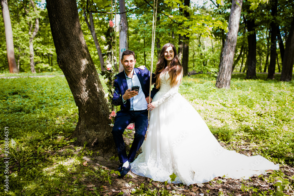 Cute couple walking in the forest near a swing with a decor Cute couple walking in the forest near a swing with a decor