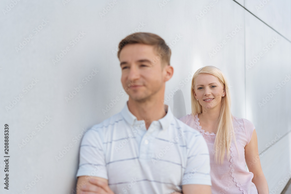 Young man and woman leaning on a white wall Young man and woman leaning on a white wall