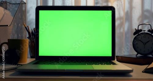 Laptop with green screen. Dark office. Perfect to put your own image or video.Green screen of technology being used. Chroma Key laptop