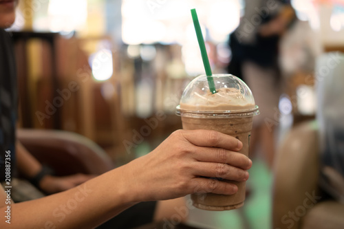 Woman holding plastic glass of iced coffee with milk photo
