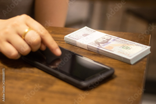 hand touch mobilephone and american dollar banknote on table
