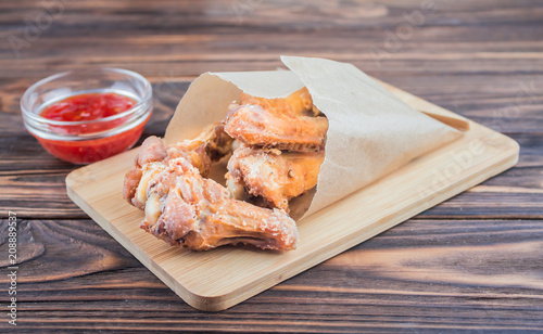 deep-fried chicken wings with tomato sauce, on a wooden background