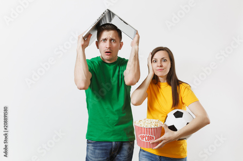 Fun shocked couple, woman man, football fans in yellow green t-shirt cheer up support team with soccer ball, with pc laptop on head isolated on white background. Sport family leisure lifestyle concept