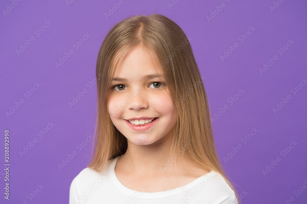 Girl on smiling face with long hair wears white shirt, violet background. Girl likes to look cute, stylish and fashionable. Kid girl with long hair looks adorable. Hairstyle and hair care concept