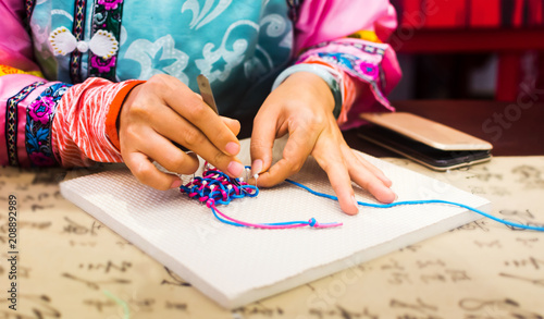 Woman making Chinese knot close up photo