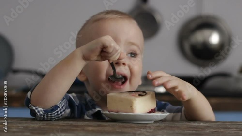 Wallpaper Mural Cute, happy, smiling blonde baby, boy is eating delicious cake at kitchen Torontodigital.ca