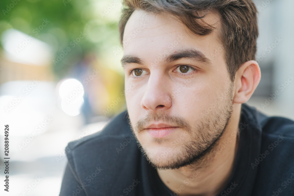 Fototapeta premium An attractive and handsome man with stylish hair and beard, interesting funny story. Portrait of a worried young man at the workplace. Stress concept.