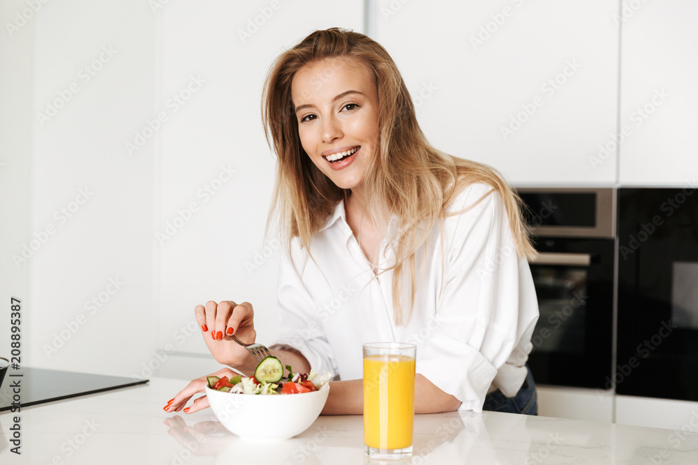 Joyful young woman eating salad from a bowl Joyful young woman eating salad from a bowl