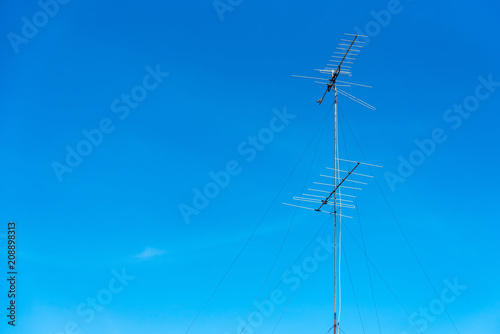 Analog tv antenna with blue sky background.