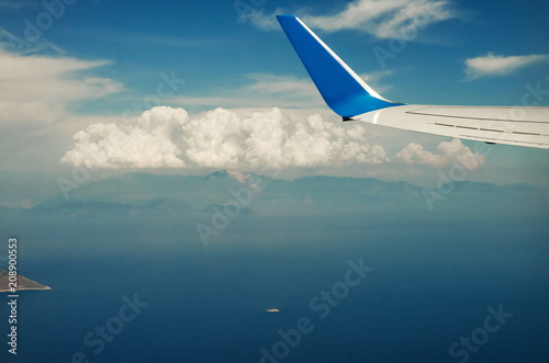 View from airplane window travel tourism. Wing of an airplane flying above the clouds over tropical island Turkey