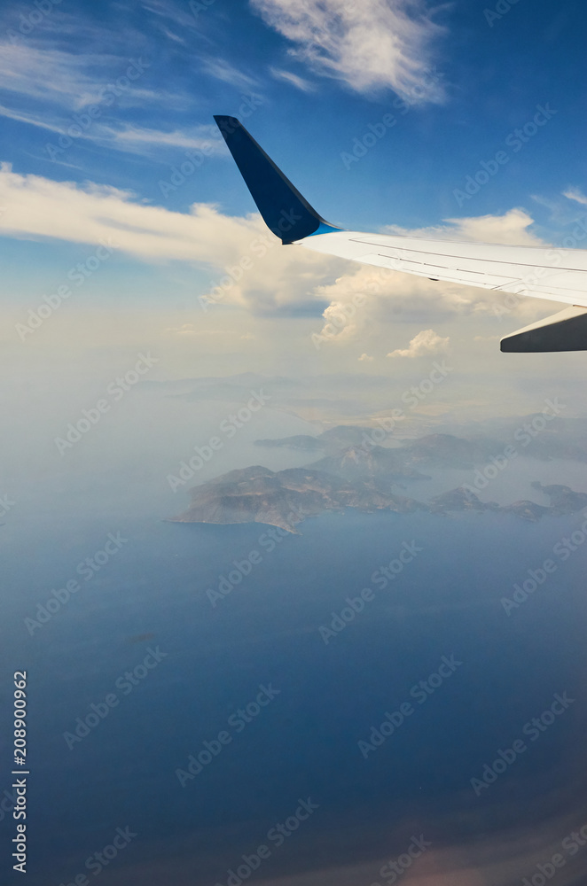 View from airplane window travel tourism. Wing of an airplane flying above the clouds over tropical island Turkey View from airplane window travel tourism. Wing of an airplane flying above the clouds over tropical island Turkey