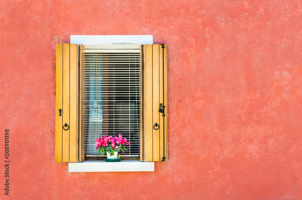Window with wooden shutters on the red wall. Colorful houses in Burano island, Venice, Italy