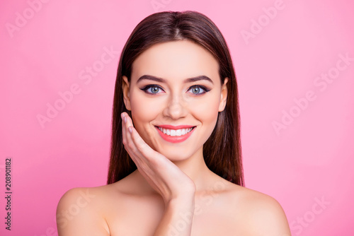 Close up portrait of pretty cute lovely adorable glamorous sensitive stylish with toothy beaming smile gorgeous girl with brown silky smooth hair touching cheek with a hand isolated on pink background