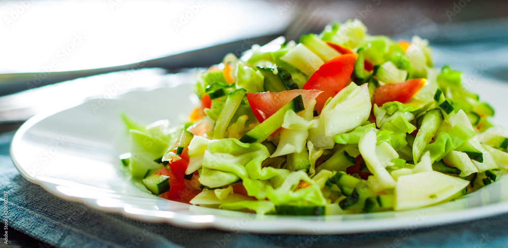 fresh vegetables salad with cabbage, tomato and cucumber in plate on table