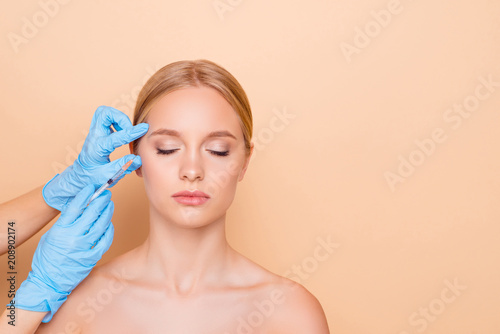 Perfection concept. Nude natural  cute model with close eyes making lifting botox injection near eyes isolated on beige background with copy space empty place for product photo