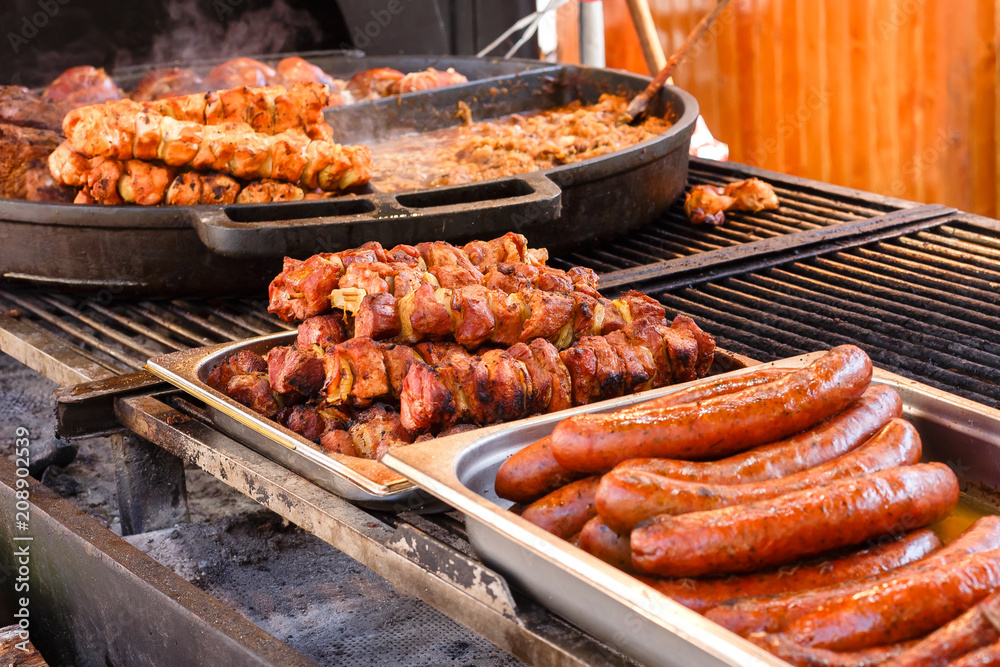 Delicious fresh fried meat and sausages on a pans in a street cafe.