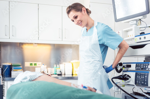 Nurse preparing herself and patient for endoscopy in examination room of hospital