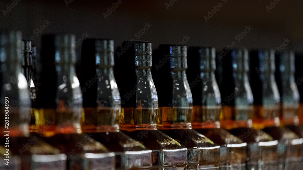 Necks of the bottles of alcohol standing in a row