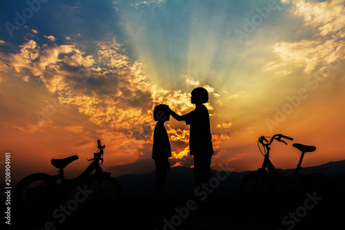  Silhouette of two happy children whit bicycle playing at sunset