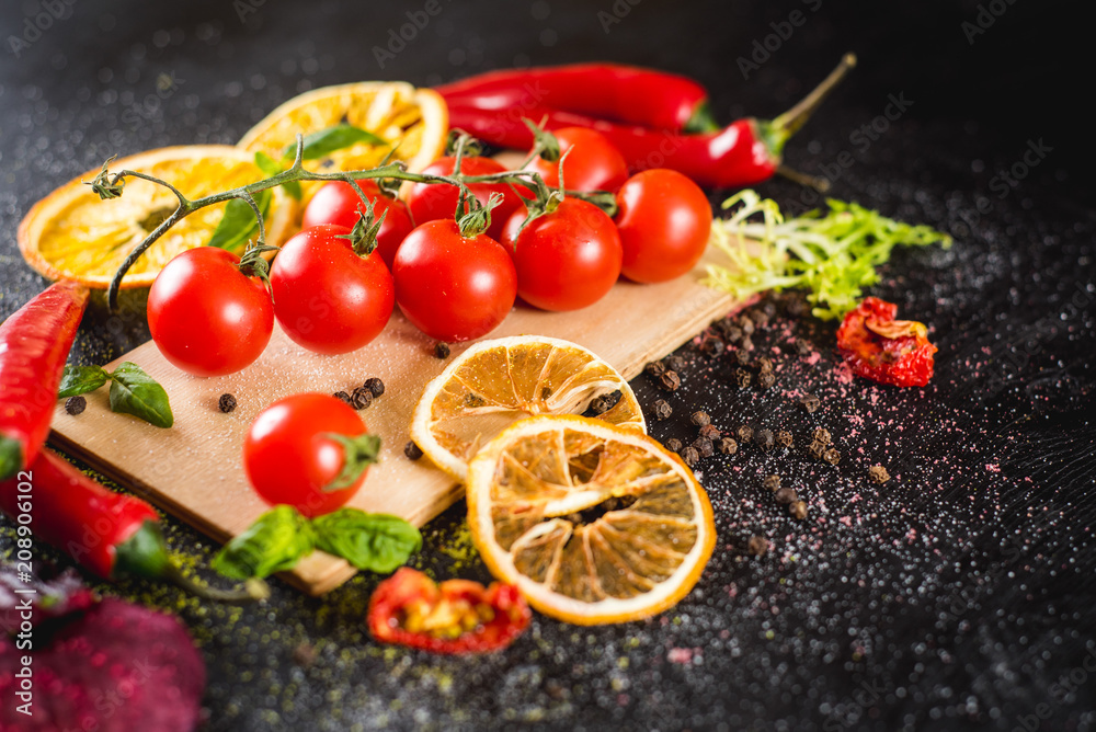 Fresh cherry tomatoes with spices on black background Fresh cherry tomatoes with spices on black background