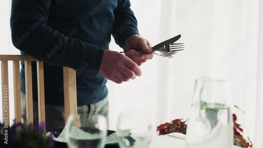 A senior man setting the table for dinner at home. A senior man setting the table for dinner at home.