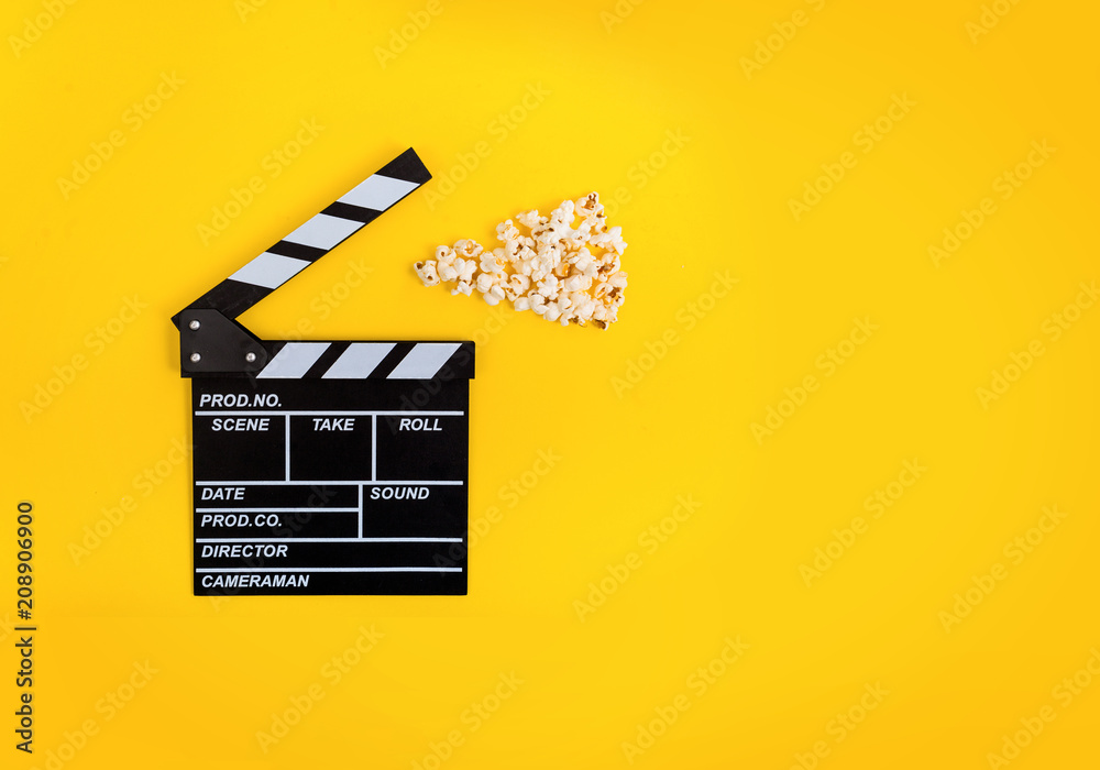 Cinema background. Popcorn and clapperboard on yellow background