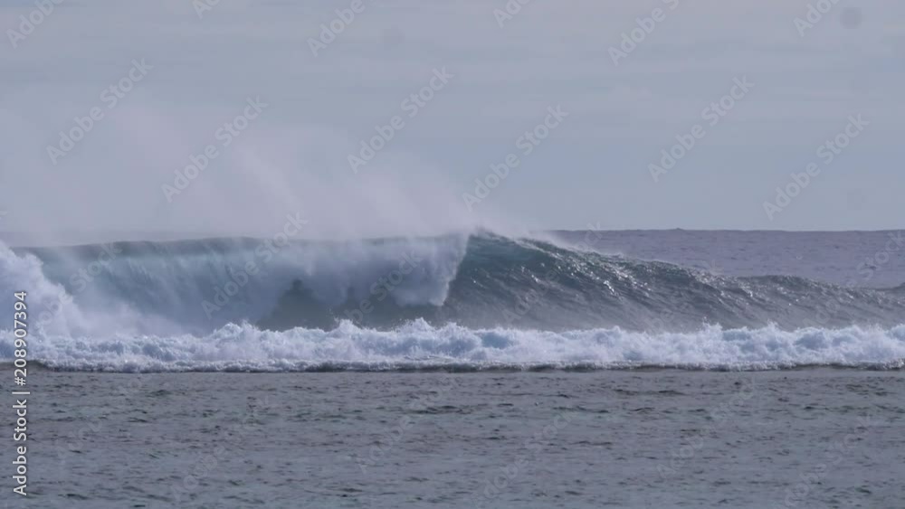 SLOW MOTION: Big spraying tube wave rolls towards the remote beach in the bright summer sunshine. Breathtaking shot of huge barrel wave coming from ocean splashing on a perfect day near Cook Islands. SLOW MOTION: Big spraying tube wave rolls towards the remote beach in the bright summer sunshine. Breathtaking shot of huge barrel wave coming from ocean splashing on a perfect day near Cook Islands.