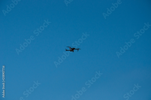 Black quadrupter with propellers flies in the sky and photographs landscapes