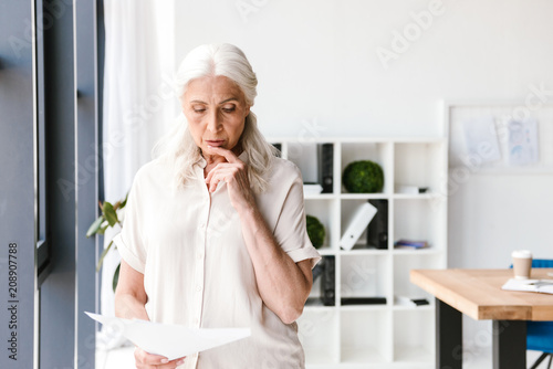 Pensive mature business woman analyzing documents
