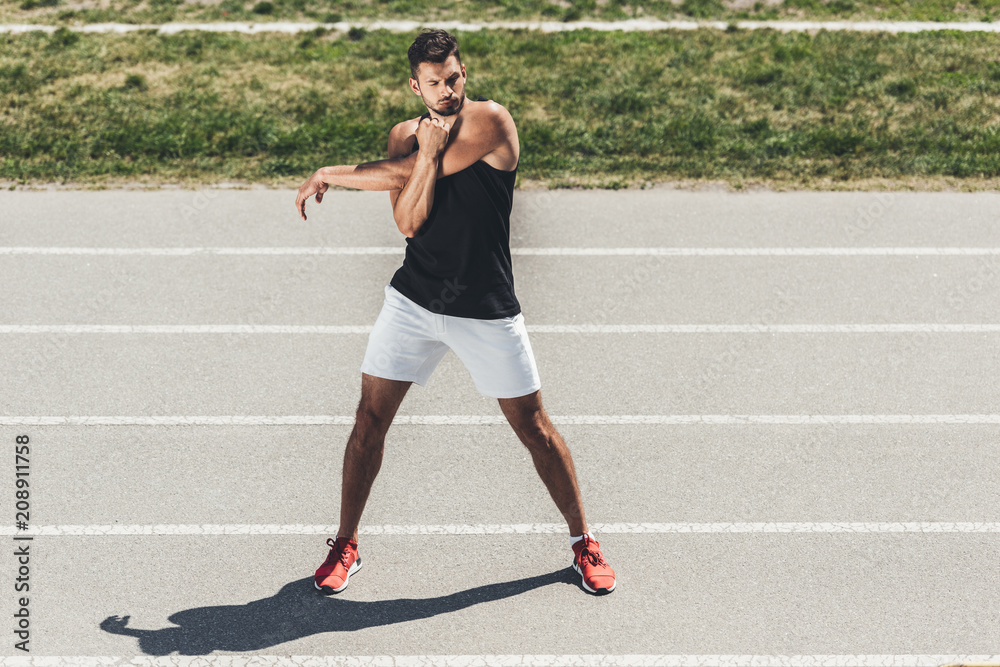 Obraz premium male athlete stretching on running track at sport playground