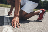 cropped image of male sprinter in starting position on running track
