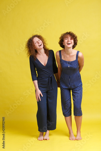 Crazy best friend. Two Happy European female having fun together, Glad young best female friends with broadly smile posing over yellow studio bacground. Female friendship concept