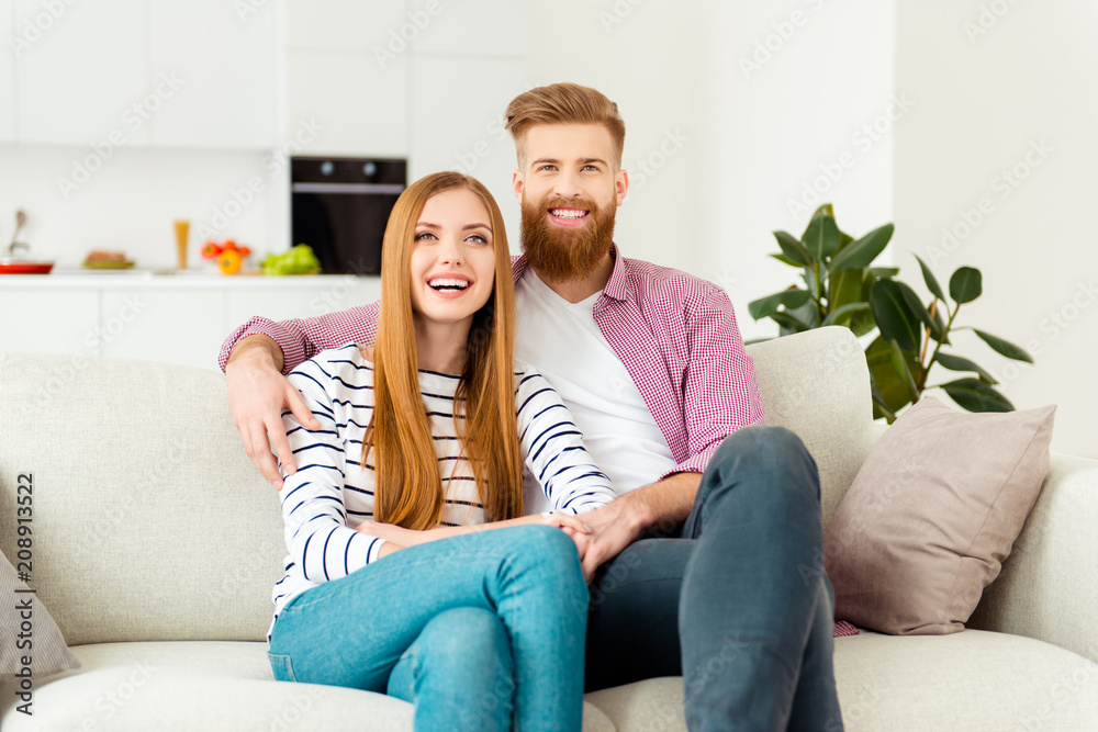 Leisure lifestyle room house emotion expressing concept. Excited lovely boy and girl enjoying funny comedy on tv wearing casual jeans shirt sweater outfit sitting on beige soft divan in living room
