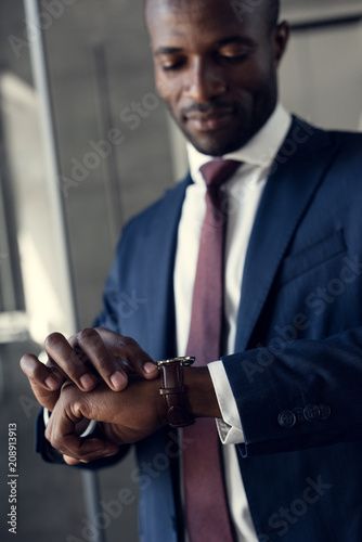 close-up portrait of handsome young businessman in stylish suit looking at wristwatch