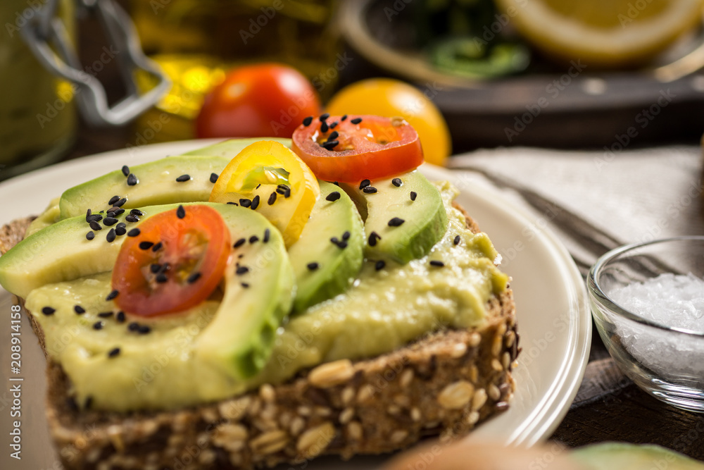 Avocado Spread and Slices with Cherry Tomato and Black Sesame on Wooden Background as Vegetarian Food Concept Avocado Spread and Slices with Cherry Tomato and Black Sesame on Wooden Background as Vegetarian Food Concept