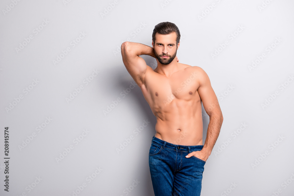 Portrait of sensual handsome attractive concentrated flirty coquettish seductive alluring tempting sexy with perfect body touching his neck holding hand in denim jeans isolated on gray background