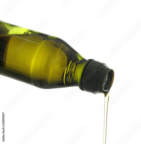 Pouring of olive oil from bottle on white background