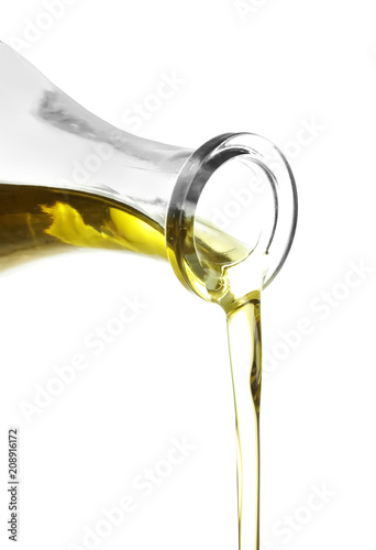 Pouring of olive oil from bottle on white background