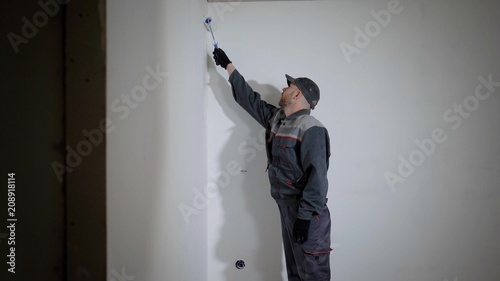 Working man is priming wall in flat. photo
