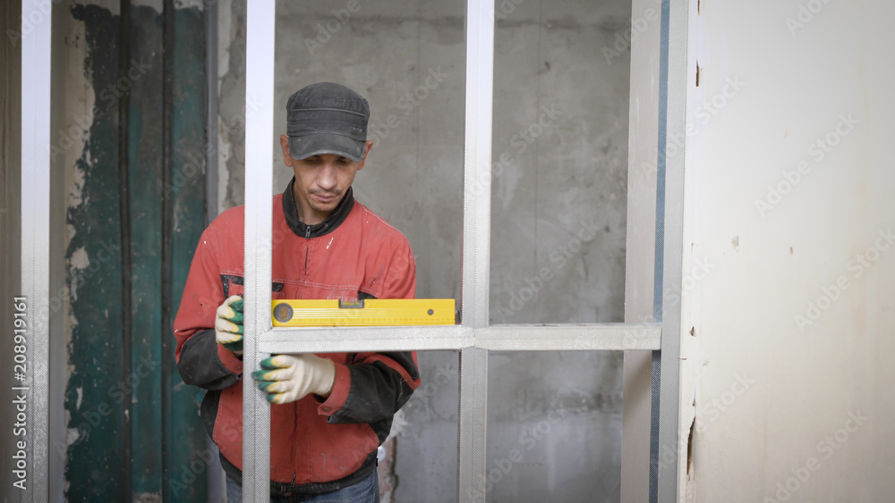 master is installing horizontal metal beams in aluminum construction, leveling with building level and fixing by screws master is installing horizontal metal beams in aluminum construction, leveling with building level and fixing by screws