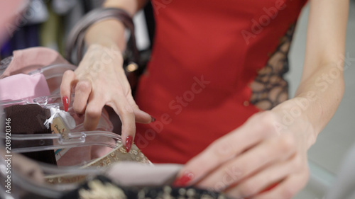 close shot on a woman's hands, who selects fashion items in an expensive boutique, she hshet to update the wardrobe